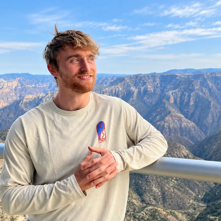Joe Colvin smiling, leaning on a railing above a wide canyon